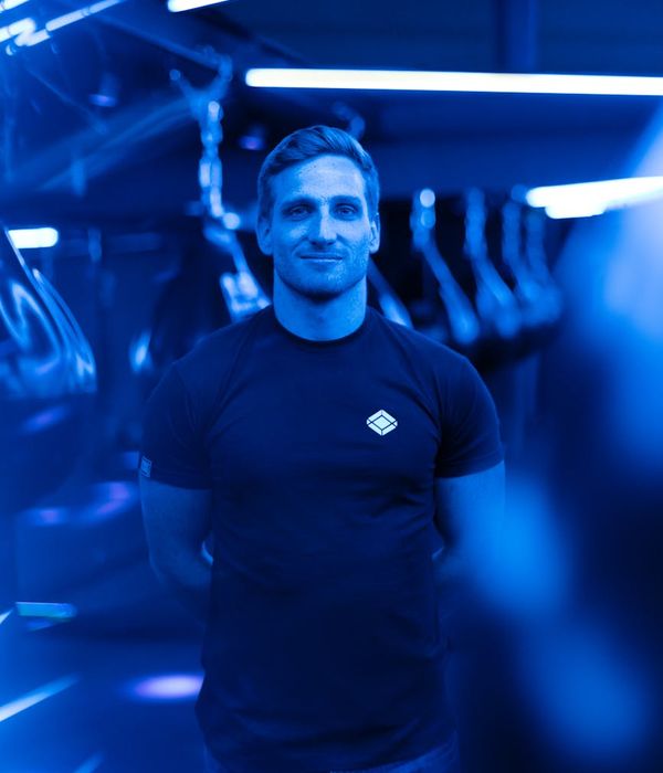 Man performing a core strength exercise in a dark, modern setting with mint light accents.